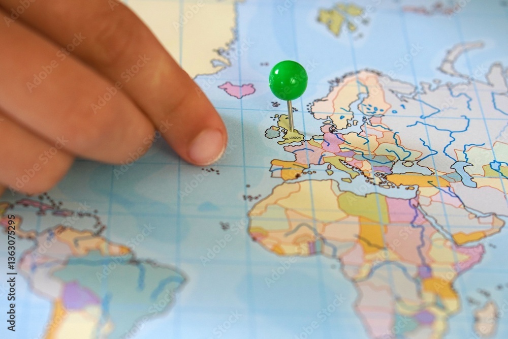 hand placing a pin on united kingdom as next travel destination to go to london to learn english. hand placing a pin on united kingdom as next travel destination to go to london to learn english.