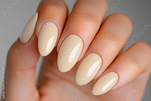 Woman's hand with elegant pastel yellow almond-shaped manicured nails, showcasing nail art, beauty trends, and salon services.