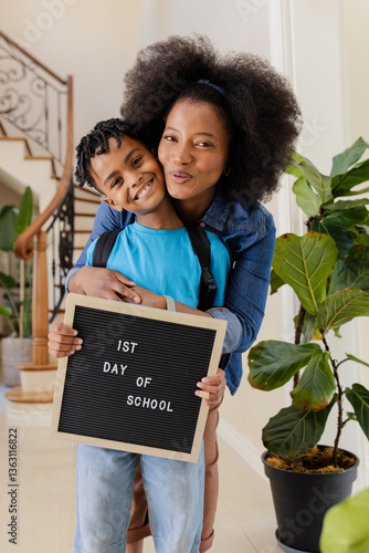 African American mother hugging son holding 1st Day of School sign, both smiling