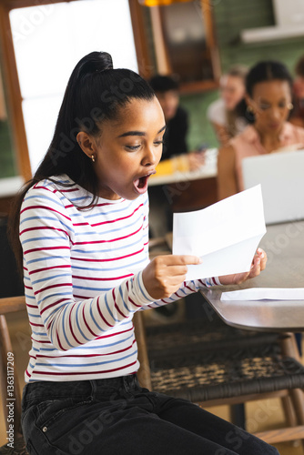 Reading college acceptance letter at school, teen girl in showing surprise and excitement, at home
