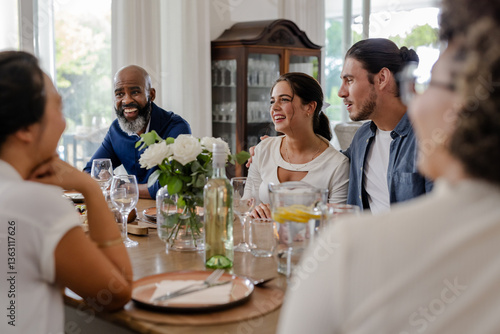 Friends enjoying conversation around dining table during small casual wedding celebration, at home