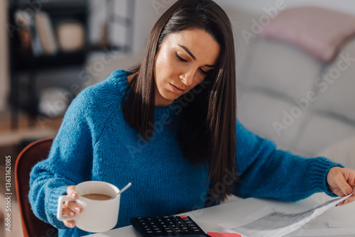 Photography Woman drinking coffee and managing home finances with calculator and documents