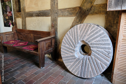 Bild auf Leinwand Old millstone with cutting pattern beside wooden pew in half-timbered mill