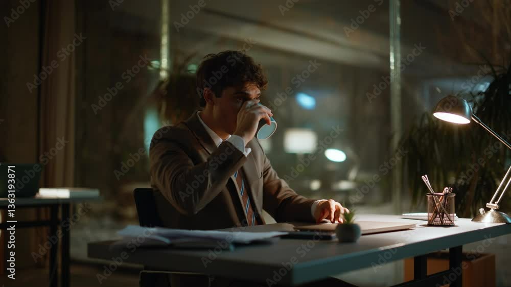 Evening manager drinking coffee at office under lamp light. Man making break Evening manager drinking coffee at office under lamp light. Man making break