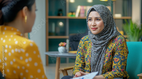 Woman in hijab talking to another person in a bright, casual office setting