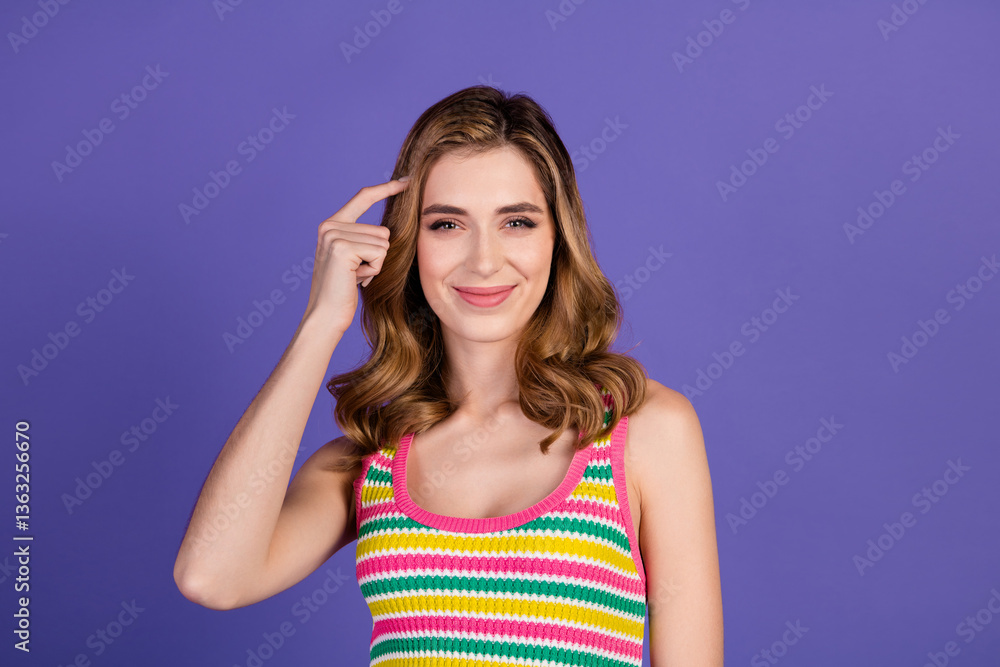 Smiling young woman in colorful striped top gesturing on purple background representing creativity, style, and positivity Smiling young woman in colorful striped top gesturing on purple background representing creativity, style, and positivity