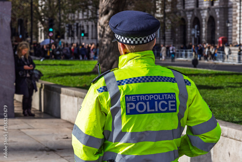 Φωτογραφία Back view of UK police officer monitoring crowd in central London park area