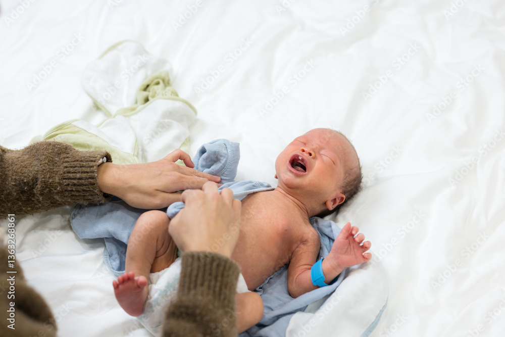 Newborn baby crying while getting clothes changed