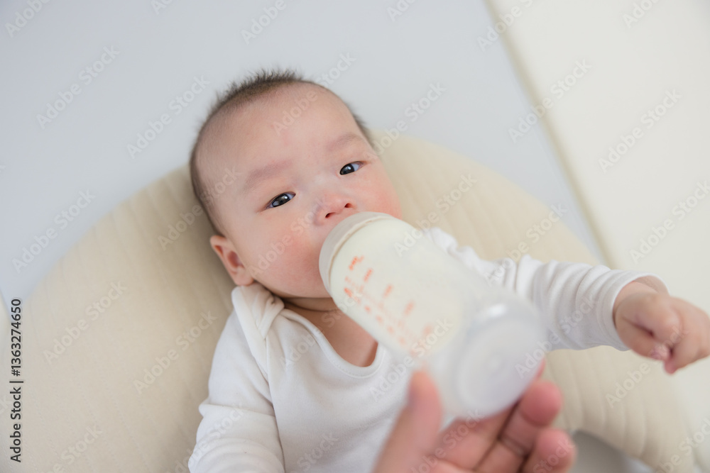 Baby drinking milk from feeding bottle