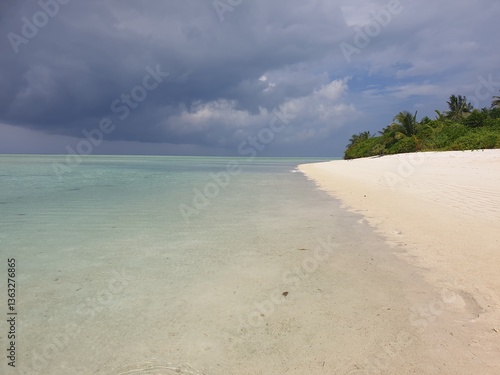 Pristine Beach and Crystal Waters Under Stormy Skies in Maldives