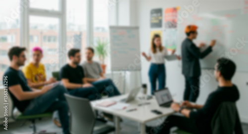 Blurry background of a modern office with a large window. Office full of young people working.