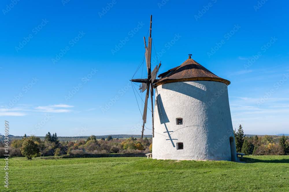 Rustic stone windmill in a grassy field