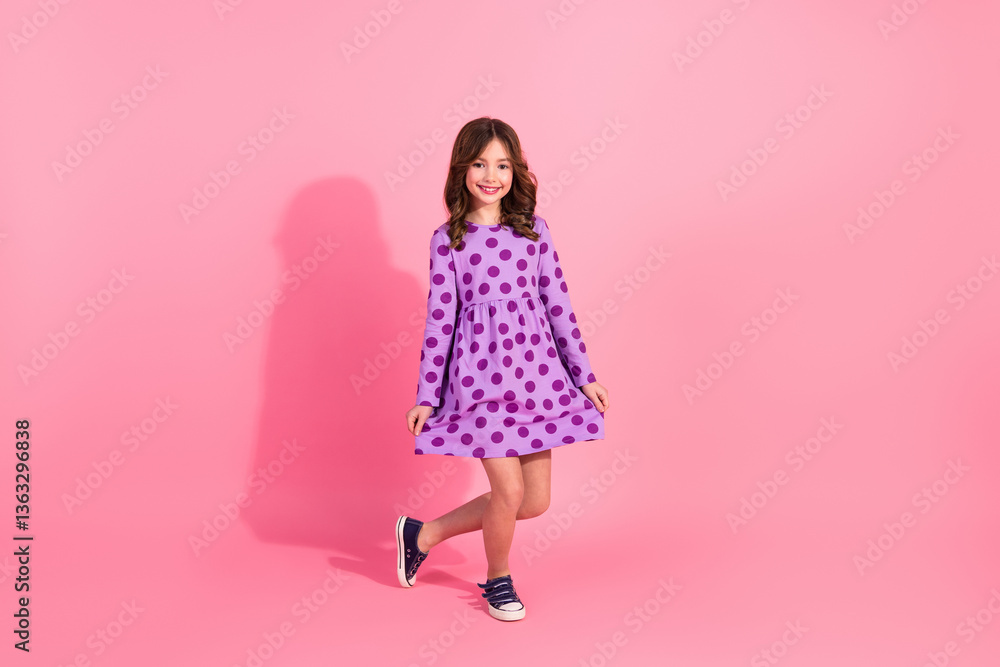 Charming pretty girl in a stylish polka dot dress against a pastel pink background showcasing fashion and trendy casual wear for kids. Charming pretty girl in a stylish polka dot dress against a pastel pink background showcasing fashion and trendy casual wear for kids.