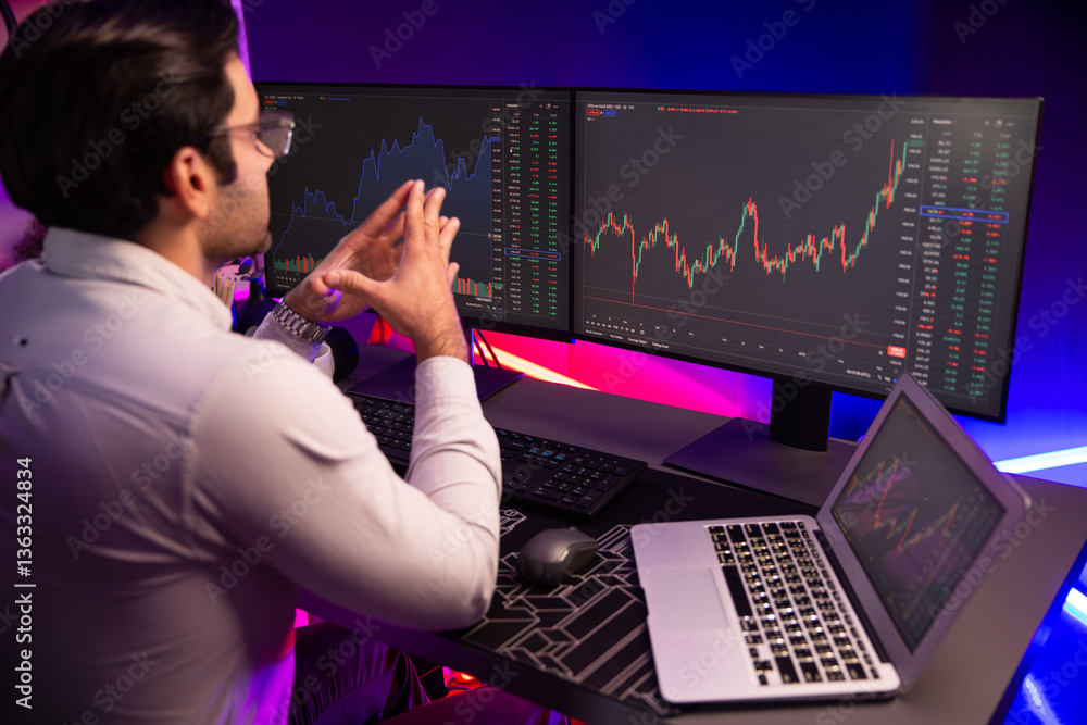© InfiniteFlow - Smart trader businessman concentrating on dynamic stock exchange investment on pc and laptop showing on screen with high profit in searching market at neon light office in dark room night. Surmise. © InfiniteFlow - Smart trader businessman concentrating on dynamic stock exchange investment on pc and laptop showing on screen with high profit in searching market at neon light office in dark room night. Surmise.