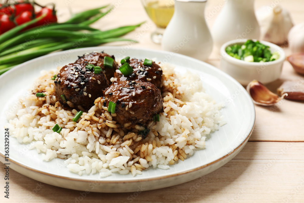 Delicious rice with meatballs, sauce and green onions on white wooden table, closeup Delicious rice with meatballs, sauce and green onions on white wooden table, closeup