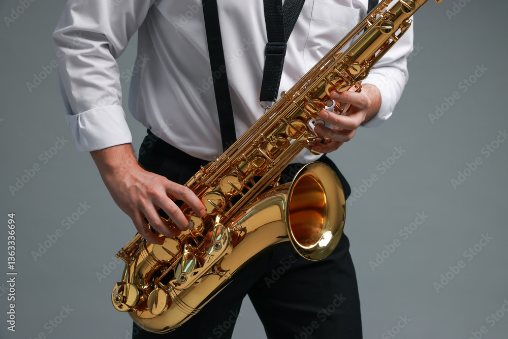 Fototapeta premium Professional musician playing saxophone on grey background, closeup