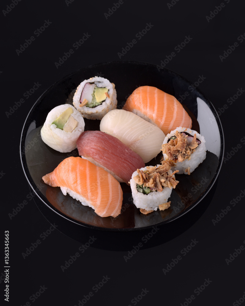 Variety of delicious nigiri and maki sushi displayed on a black plate Variety of delicious nigiri and maki sushi displayed on a black plate