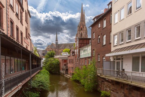 View of Lahn river with residential buildings and Elisabeth Church in Marburg Germany under cloudy sky