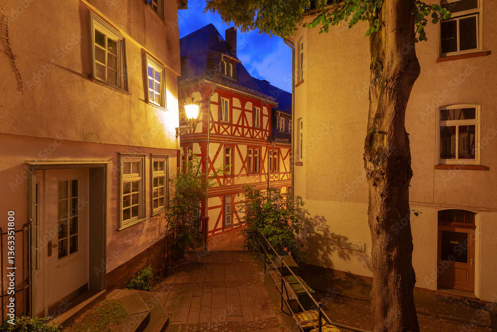 Illuminated fachwerk house in the old town of Marburg Germany with narrow alley and evening light