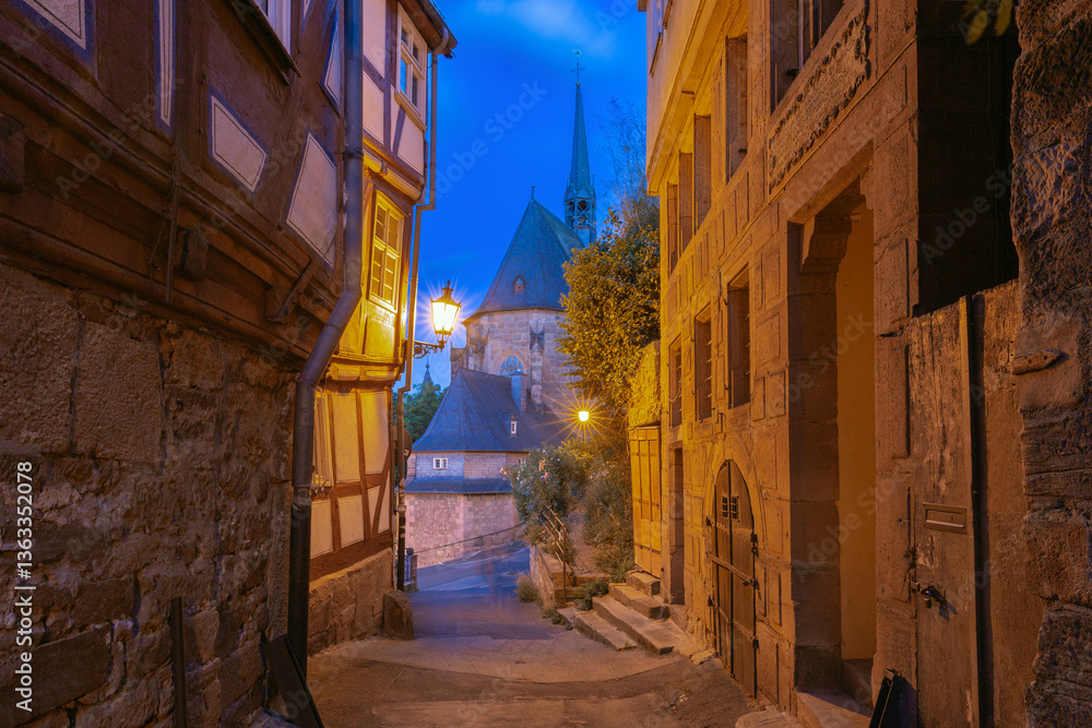 Illuminated fachwerk house in the old town of Marburg Germany with narrow alley and evening light