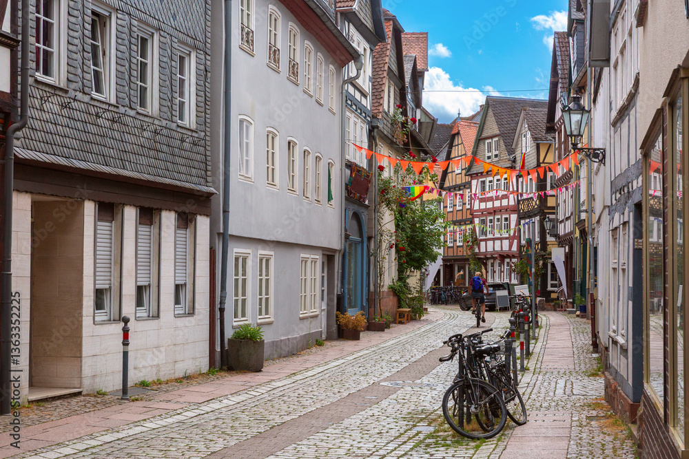 Fachwerk houses along cobblestone street in the old town of Marburg Germany with bicycles and colorful flags