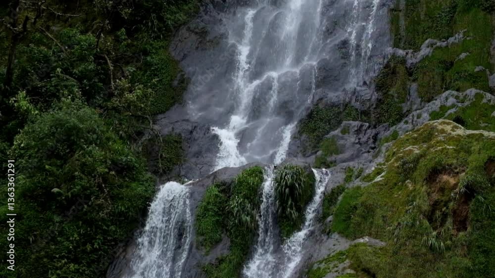 A waterfall flowing rapidly through green mossy rocks.Part of a mountain waterfall in a tropical forest. Ecological and environmental concept. Footage 4K, 60Fps A waterfall flowing rapidly through green mossy rocks.Part of a mountain waterfall in a tropical forest. Ecological and environmental concept. Footage 4K, 60Fps