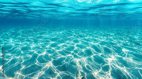A serene underwater view showcasing crystal-clear turquoise water with sunlit patterns dancing on the sandy floor.