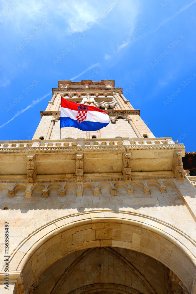 Croatian flag blowing in the wind on the bell tower of The Cathedral of St. Lawrence, landmark in Trogir, Croatia.