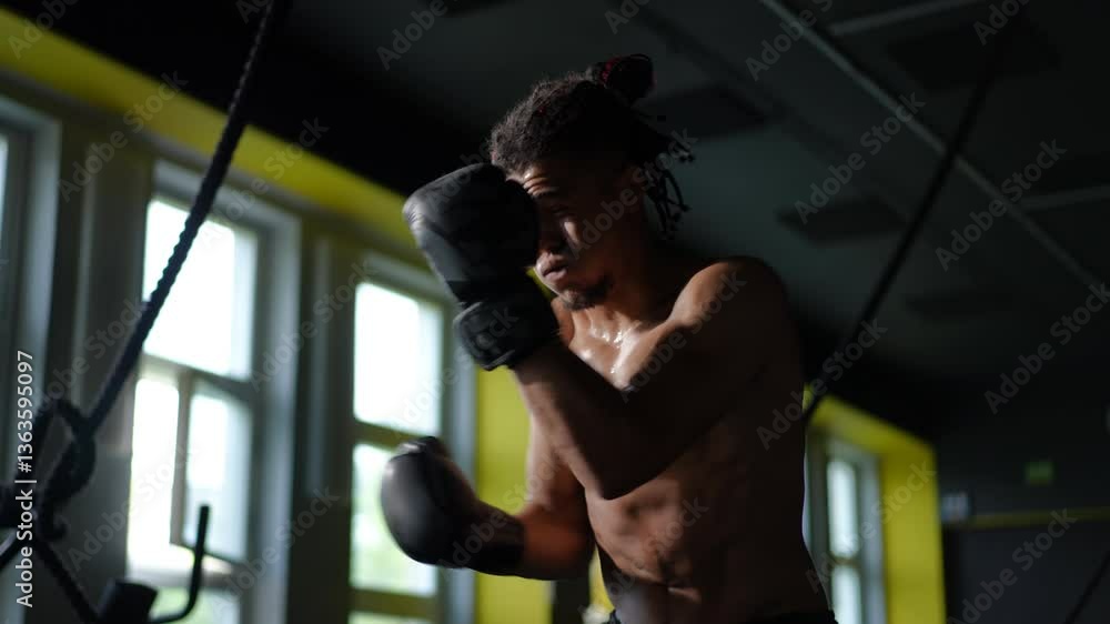 A dedicated and focused boxer is vigorously training, showcasing immense strength and commitment in the gym setting A dedicated and focused boxer is vigorously training, showcasing immense strength and commitment in the gym setting