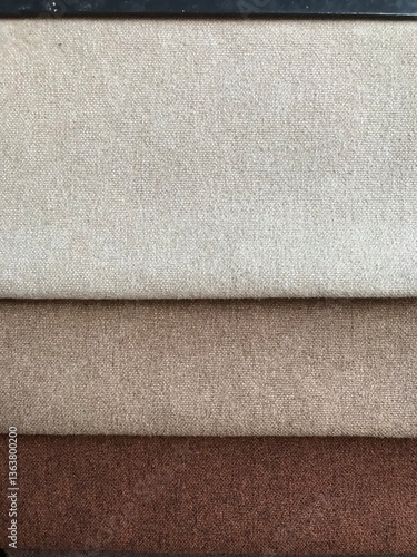 Close-up of layered fabric samples in beige, brown, and tan, showcasing textures and colors, studio shot