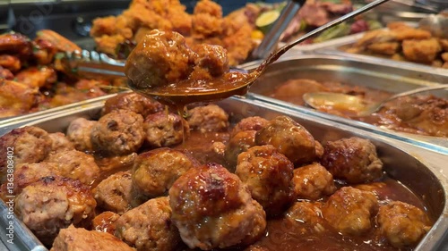 meatballs in the buffet Deep fried foods such as Chicken Drumsticks, Meatballs and Torfu in stainless steel trays, being kept warm inside a glass display counter cabinet. In a local buffet restaurant.