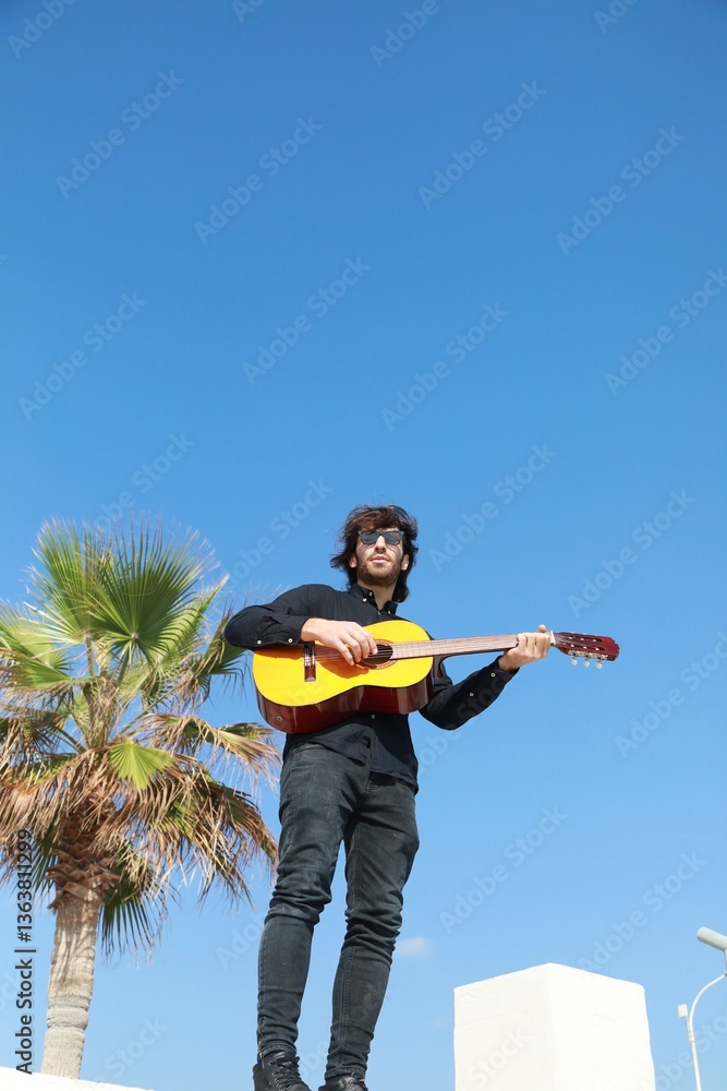 Naklejka premium Man Plays Classical Guitar On A Day Stand In The Park