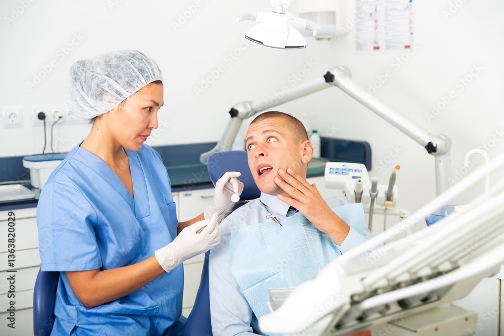 Obraz premium Male patient shows sick tooth to a dentist in a dental clinic