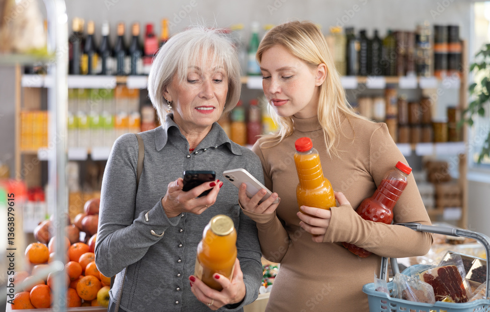 Fototapeta premium Young woman with senior female relative in store scan QR code on juice label. In mobile app, buyer receive information about drink. They check manufacturer data in registry database of national agency