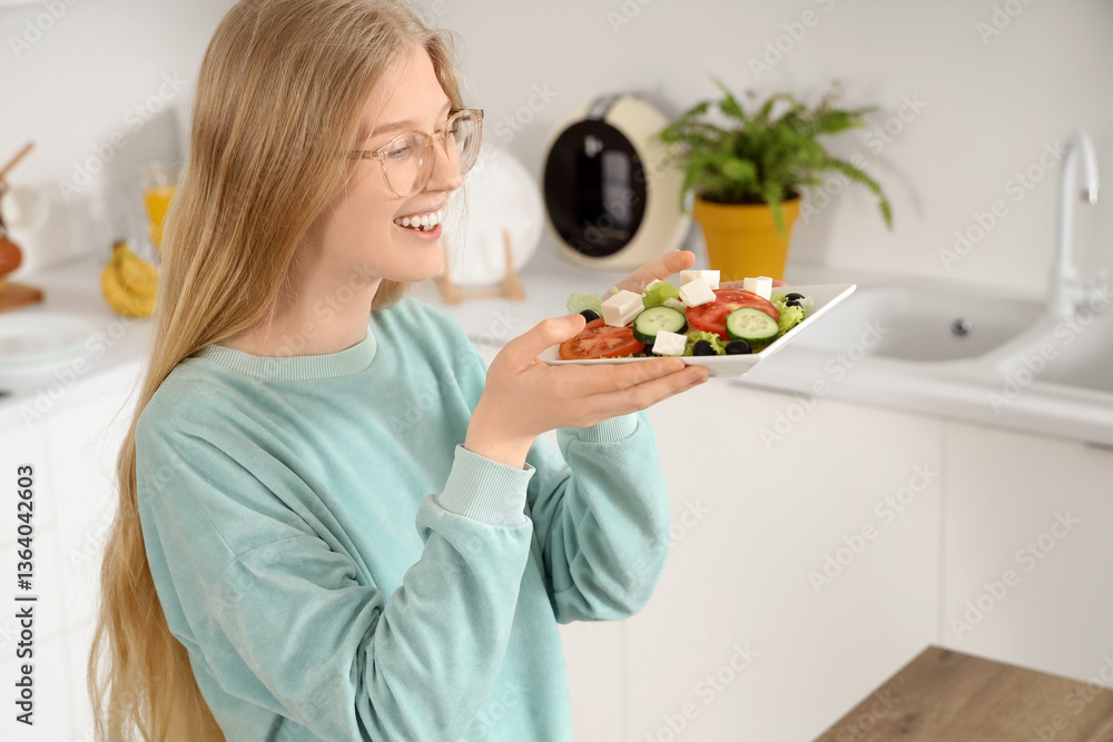 Happy young woman holding plate of tasty salad with feta cheese in kitchen Happy young woman holding plate of tasty salad with feta cheese in kitchen