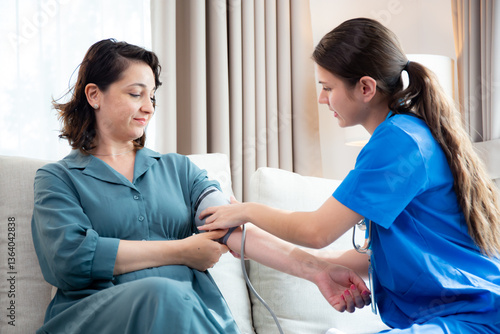 Caregiver caucasian young nurse woman measuring blood pressure with patient for checkup pulse health and examining in living room at home, nurse checkup patient for health care, medical and insurance.