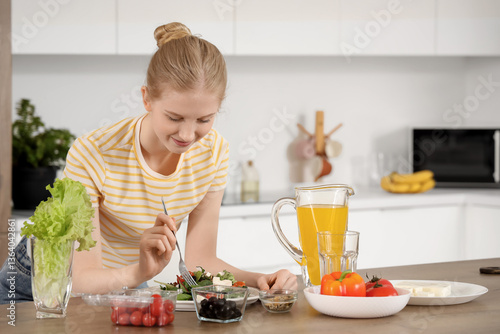 Young woman eating salad wi...
