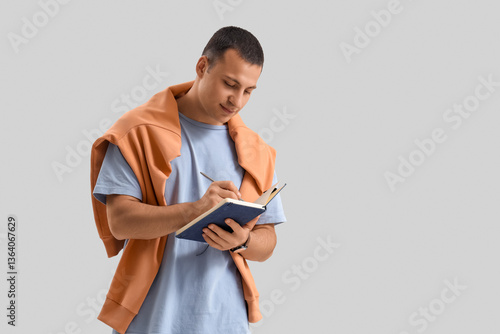 Young man writing in notebo...