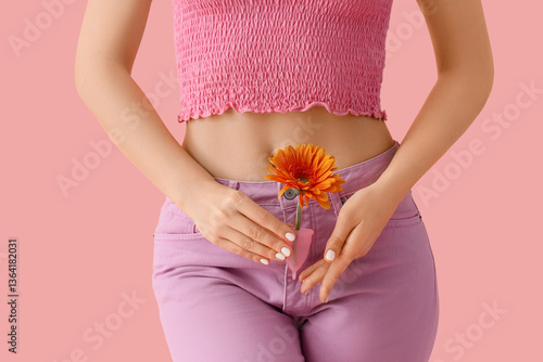 Young woman with menstrual cup and flower on pink background, closeup