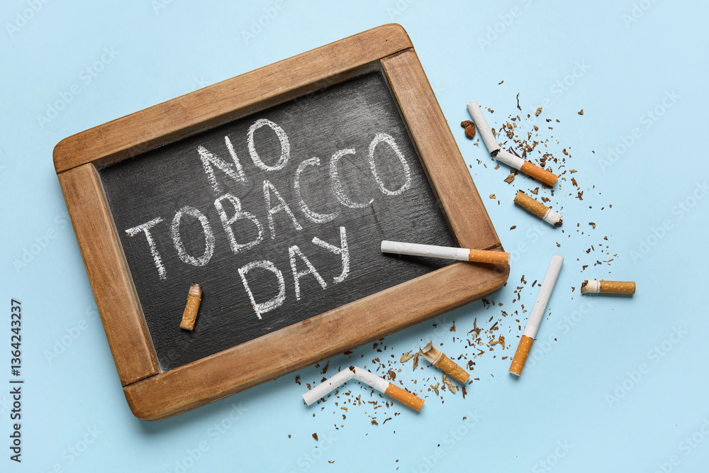 Fototapeta premium Chalkboard with text NO TOBACCO DAY and cigarette butts on blue background