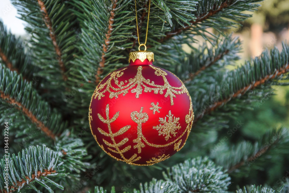 Red Christmas ball ornament on a green tree with festive decorations for the holiday season Red Christmas ball ornament on a green tree with festive decorations for the holiday season