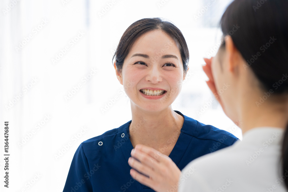 Nurse and patient sharing a smile during appointment
Description: A nurse in blue scrubs smiling warmly at a patient during a lighthearted moment in a clinical environment.