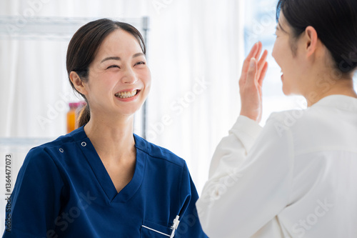 A female doctor and her female patient share a warm smile during a medical consultation in a bright clinic, showing a positive doctor-patient relationship.