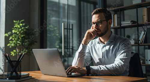 Thoughtful Man Working on Laptop in Modern Office