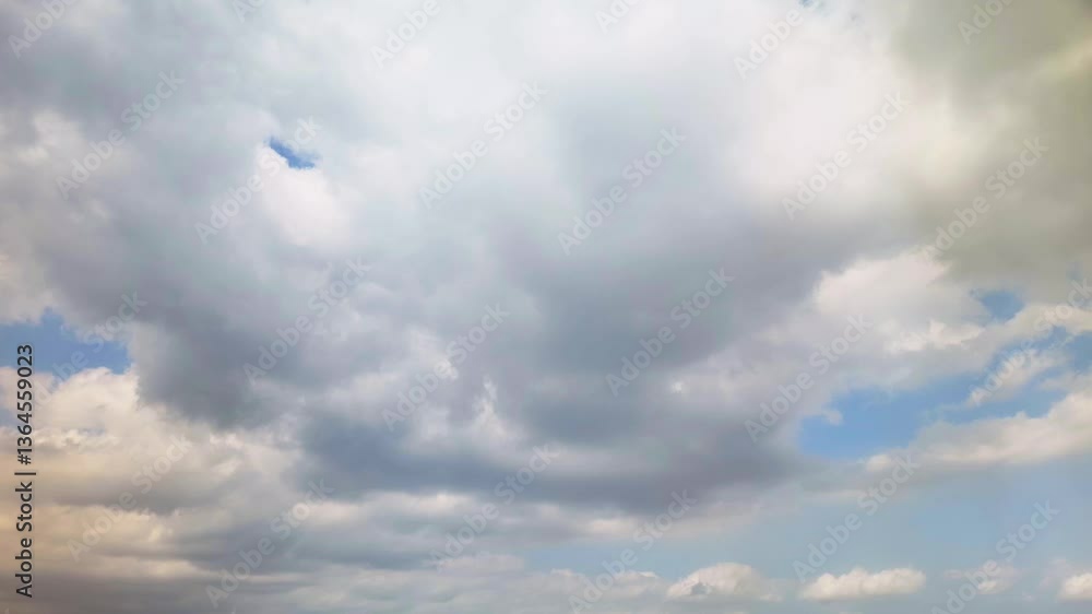 Fluffy white and gray clouds moving across a blue sky lit with slivers of golden light. Fluffy white and gray clouds moving across a blue sky lit with slivers of golden light.