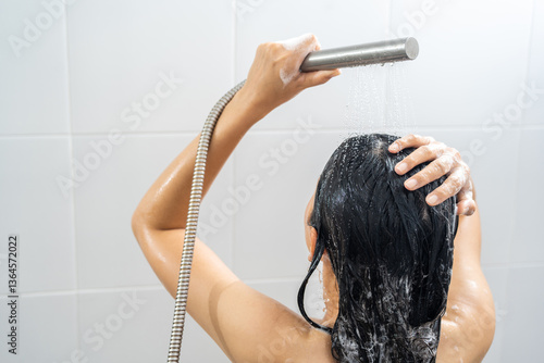 Quadro em tela Young woman in shower rinse shampoo foaming with water dripping on hair and body