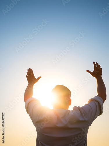 Praising the lord. Back view of a man with his arms raised to the sky in thankfulness and prayer. Themes such as Reverence, Awe, Serenity, Humility, Redemption, Resurrection, Bliss, Reflection