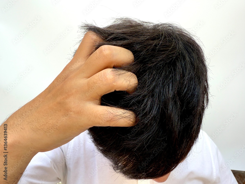 Fototapeta premium A man scratching or grabbing the top of his head, often related to scalp irritation, anxiety, or dermatological issues.