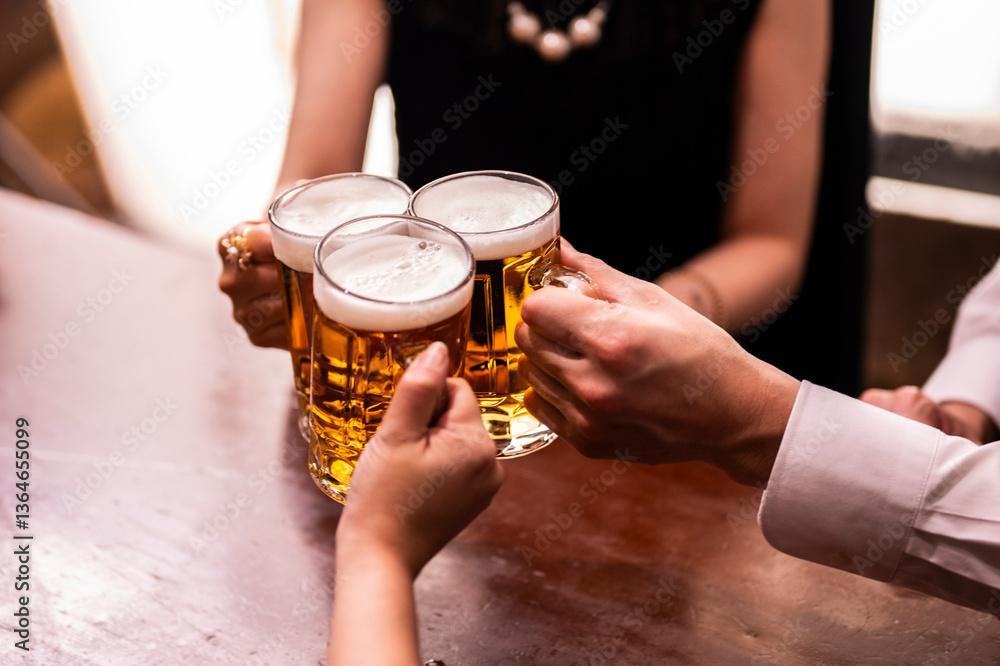A close-up overhead shot of a group of people clinking large beer mugs together in a toast over a wooden table. The scene captures the moment of celebration and friendship in a cosy bar setting.