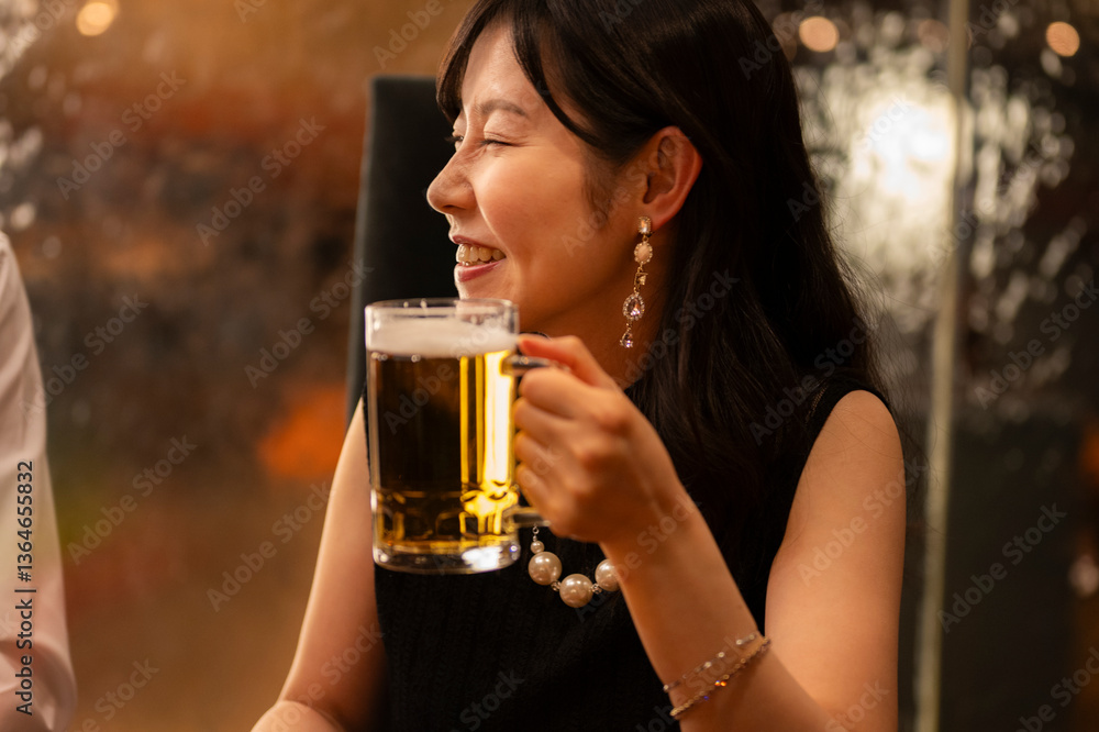 A smiling woman dressed elegantly in black raises her beer mug in a cheerful toast at a warmly lit bar. Her pearl necklace and statement earrings add a touch of luxury to the lively, social atmosphere